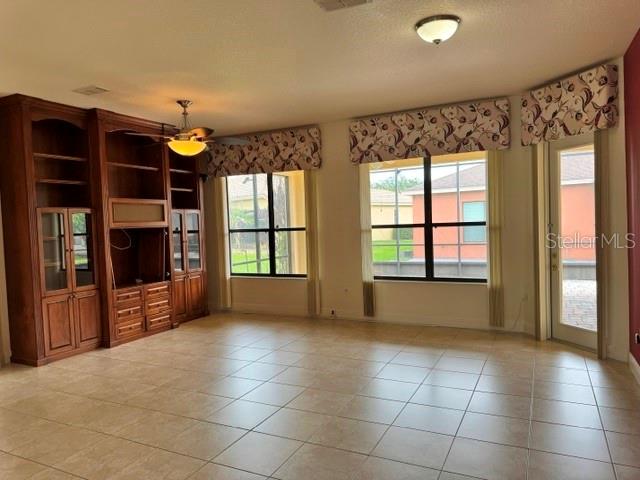 A living room features tile flooring, a large wooden built-in unit, and three windows — 896 BARCELONA DRIVE, POINCIANA, FL