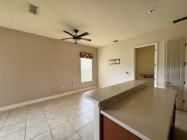 A room with tiled flooring, a ceiling fan, a window, and a kitchen counter — 896 BARCELONA DRIVE, POINCIANA, FL