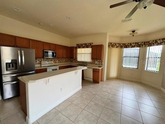 A kitchen features wood cabinets, stainless steel appliances, a breakfast bar, and tile flooring — 896 BARCELONA DRIVE, POINCIANA, FL