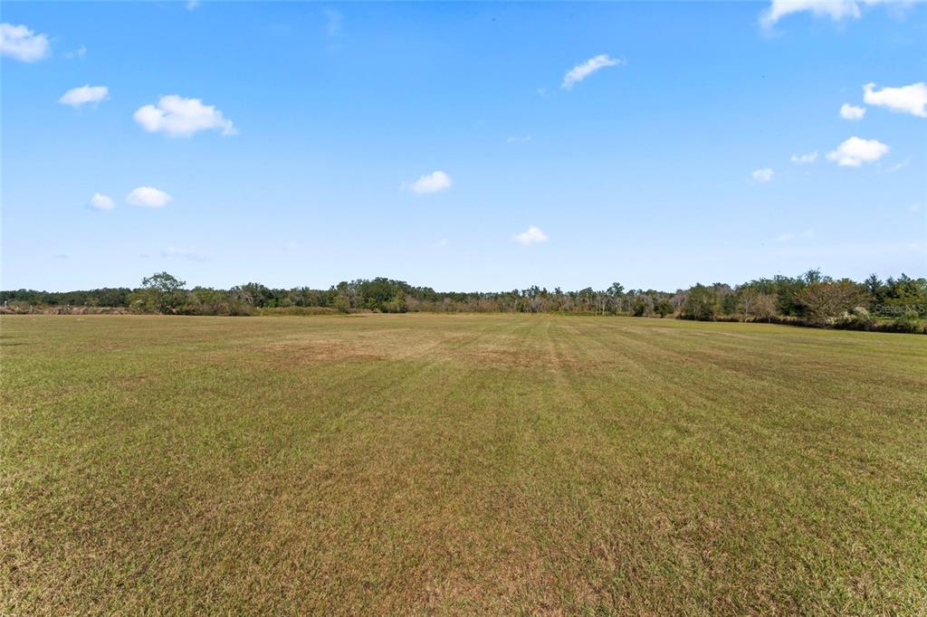 A wide, flat, grassy field under a blue sky with scattered clouds — 0 COUNTY ROAD 52, SAN ANTONIO, FL