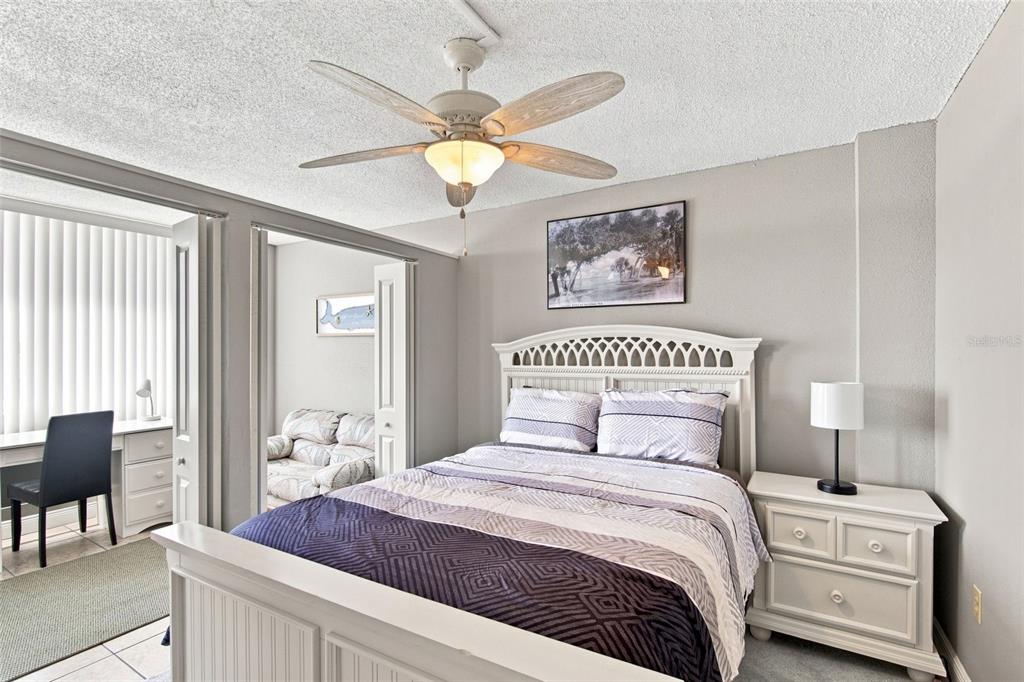 A bedroom features a white bed frame, a ceiling fan, and an adjacent office space — 935 N HALIFAX AVENUE UNIT 604, DAYTONA BEACH, FL