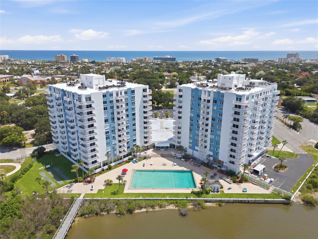 An aerial view of two high-rise apartment buildings with a swimming pool near a bay — 935 N HALIFAX AVENUE UNIT 604, DAYTONA BEACH, FL