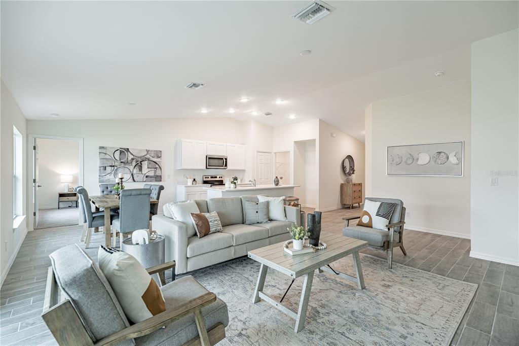 An open-concept living and dining area features light gray tile floors and neutral modern furniture — 1190 ZINNEA STREET, PORT CHARLOTTE, FL