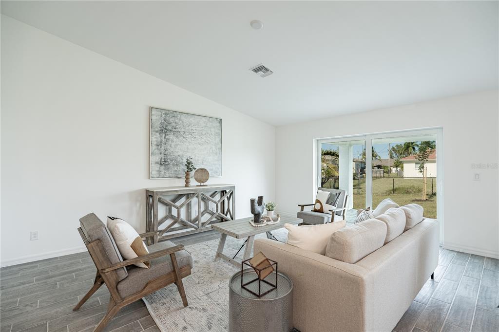 A living room features a sofa, two armchairs, a console table, and sliding glass doors — 1190 ZINNEA STREET, PORT CHARLOTTE, FL
