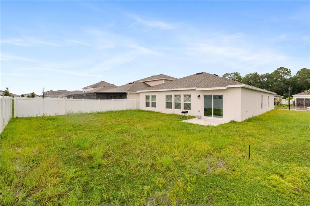 A view of a house backyard featuring a white vinyl fence and a concrete patio — 4812 WORCHESTER DRIVE, KISSIMMEE, FL