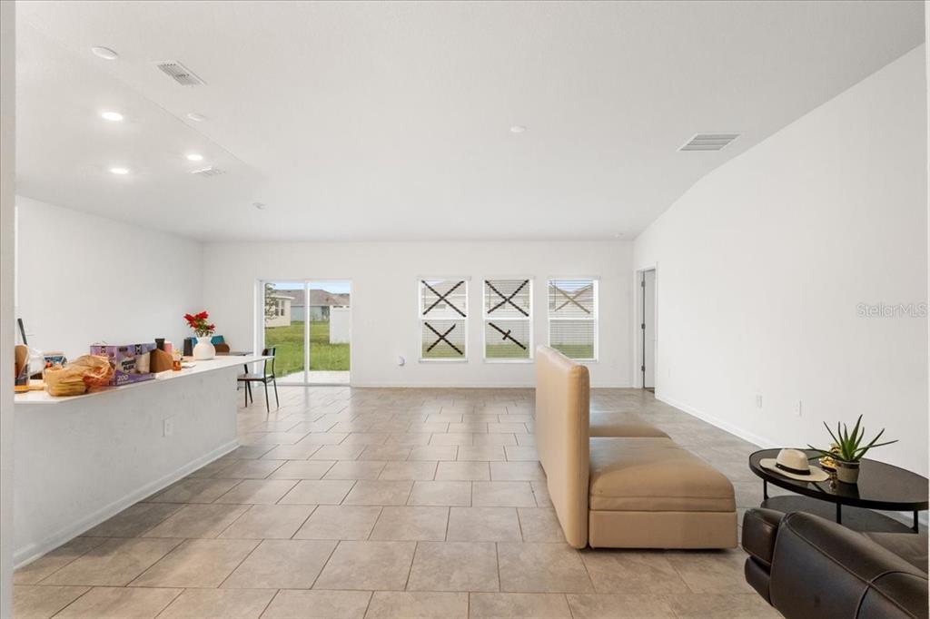 An open-concept living area features tile flooring, a kitchen island, and three windows with markings — 4812 WORCHESTER DRIVE, KISSIMMEE, FL