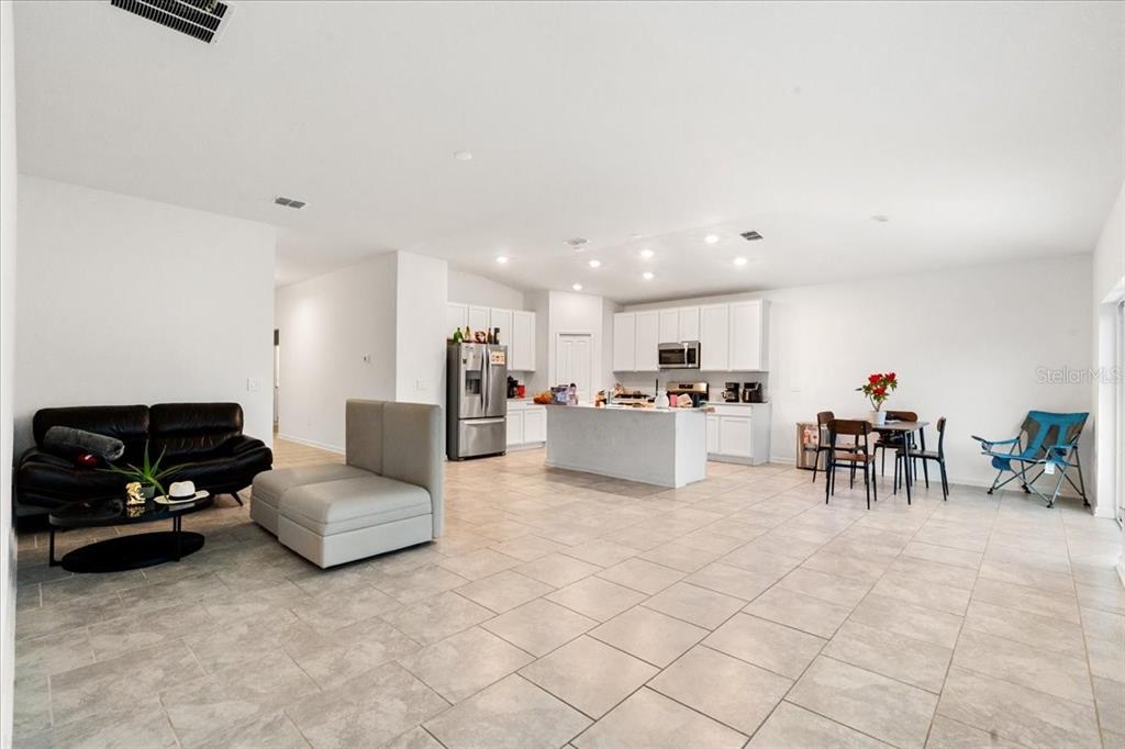 An open-concept living room and kitchen with white cabinets, a center island, and tile flooring — 4812 WORCHESTER DRIVE, KISSIMMEE, FL