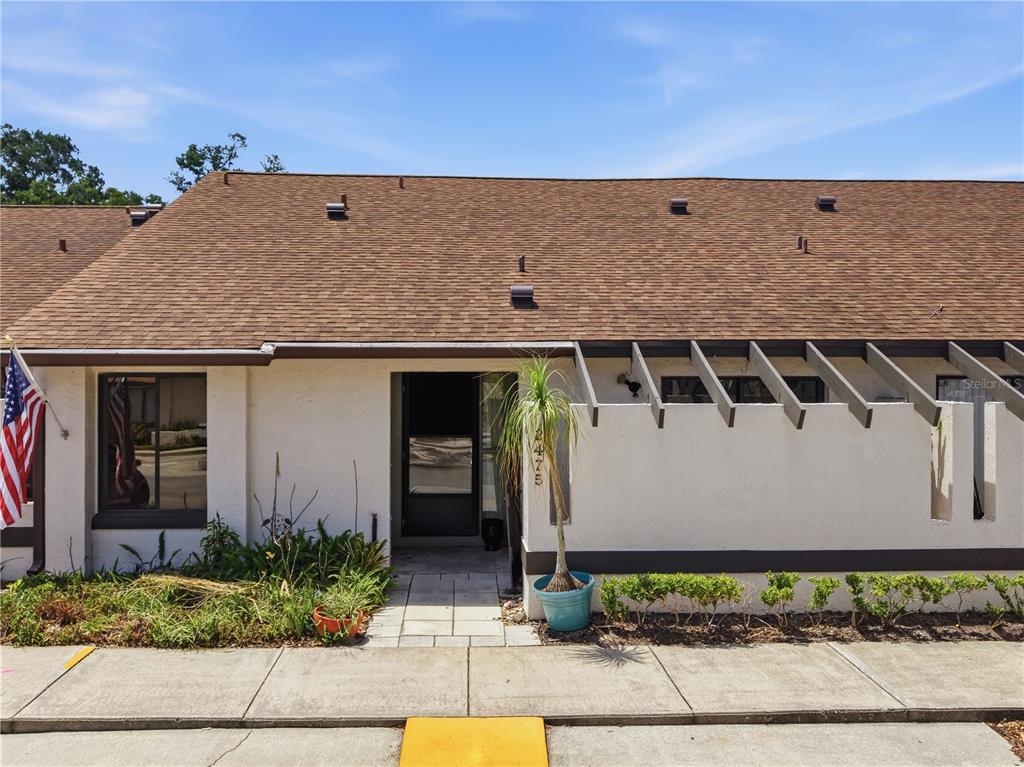The exterior of a single-story home features a brown shingled roof, stucco walls, and a pergola — 2475 TAHOE CIRCLE, WINTER PARK, FL