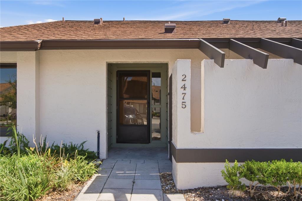 The exterior view shows a white stucco home entrance with a brown roof and walkway — 2475 TAHOE CIRCLE, WINTER PARK, FL
