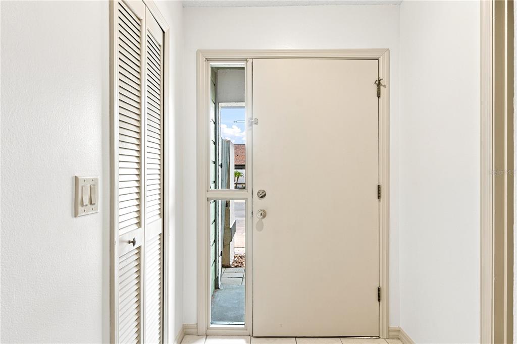 An entryway features a white door with a side window, louvered closet doors, and tile flooring — 2475 TAHOE CIRCLE, WINTER PARK, FL