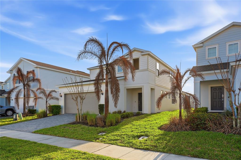 A two-story suburban house with a beige exterior, a two-car garage, and palm trees — 1177 ALOHA BOULEVARD, DAVENPORT, FL