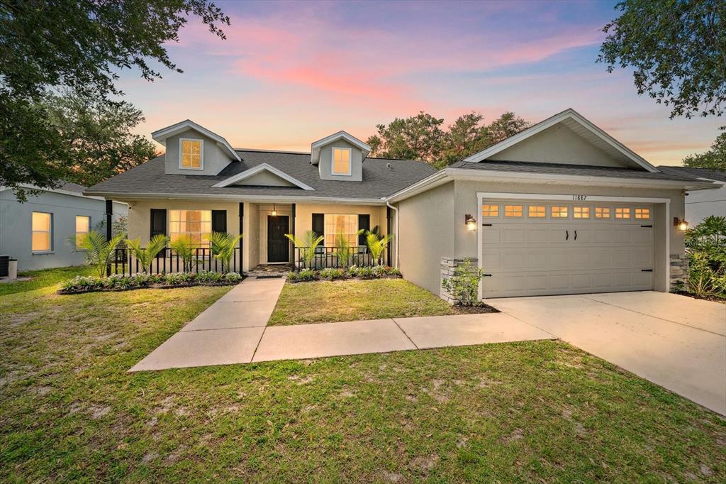 A single-story house with a two-car garage, dormer windows, and a concrete walkway — 11887 DUNSTER LANE, PARRISH, FL