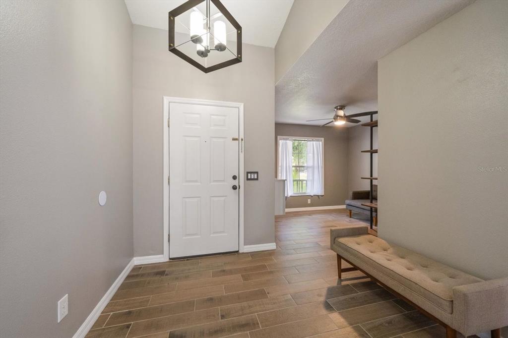 An entryway features a white door, a modern geometric light fixture, and wood-look tile flooring — 11887 DUNSTER LANE, PARRISH, FL