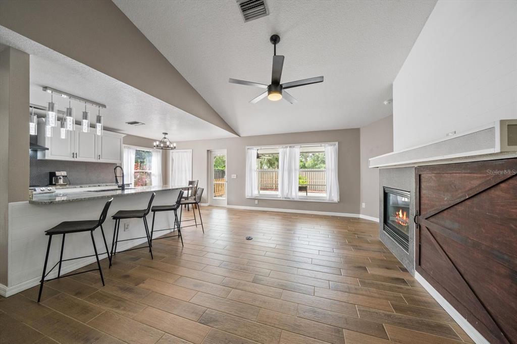 A modern open-concept living area features a kitchen island, fireplace, and wood-look tile flooring — 11887 DUNSTER LANE, PARRISH, FL
