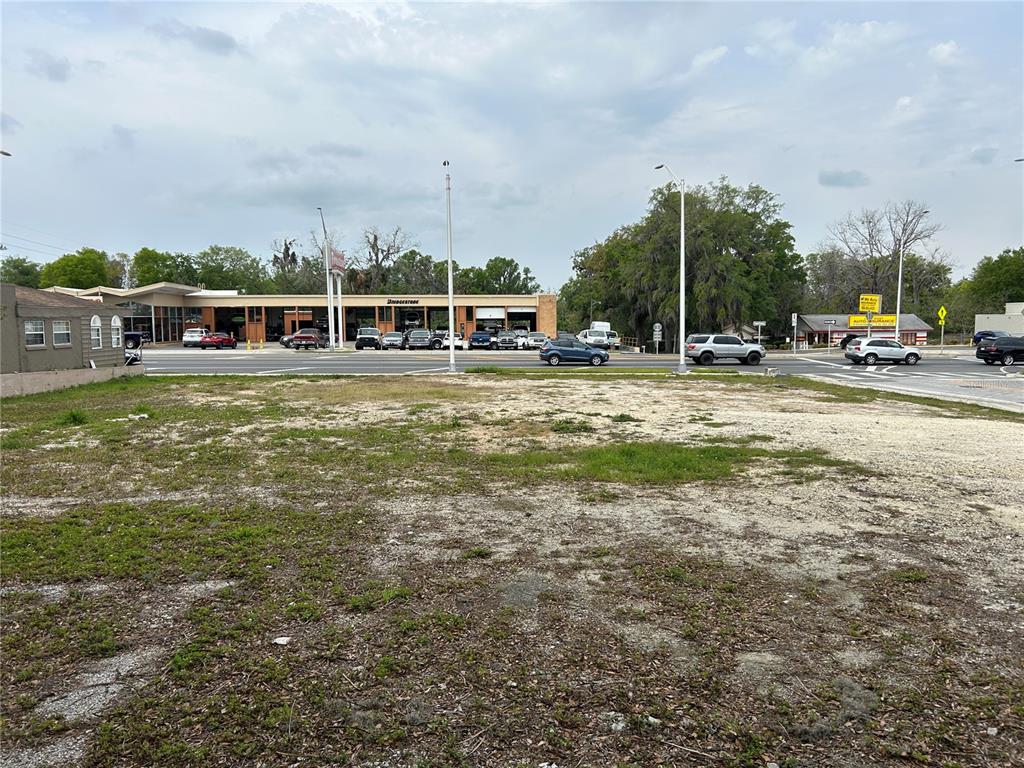 A vacant, dirt-covered lot sits in front of a commercial building and a busy road — 207 S PINE AVENUE, OCALA, FL