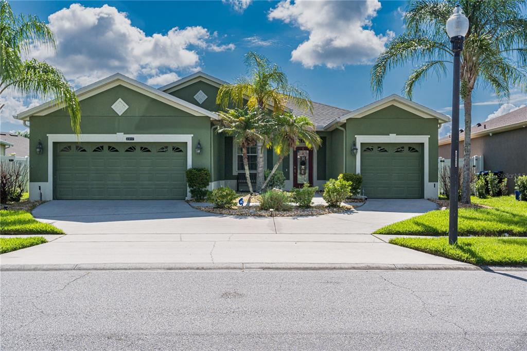 A green single-story house features a three-car garage and a central entrance with palm trees — 2317 CROSSTON CIRCLE, ORLANDO, FL