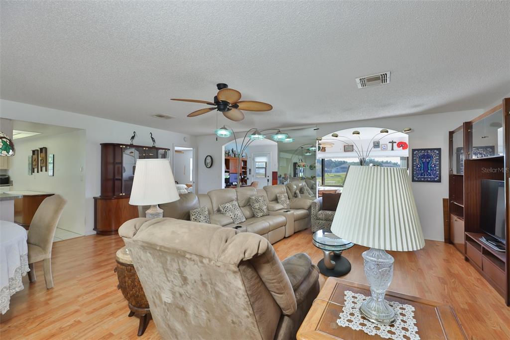 A living room features wood flooring, a ceiling fan, and large wooden display cabinets — 2611 LANCASTER DRIVE UNIT 33, SUN CITY CENTER, FL