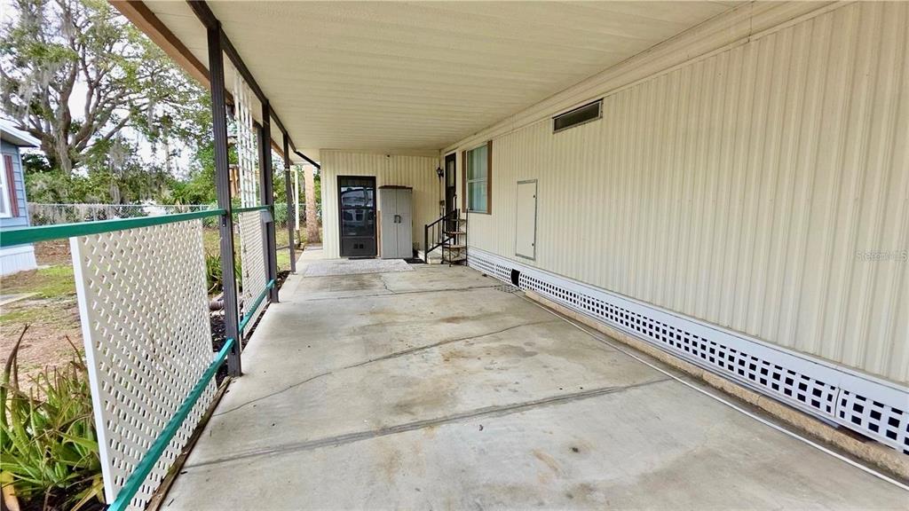 A concrete carport with a white lattice screen and a storage shed under a roof — 252 PINEWOOD DRIVE, EUSTIS, FL