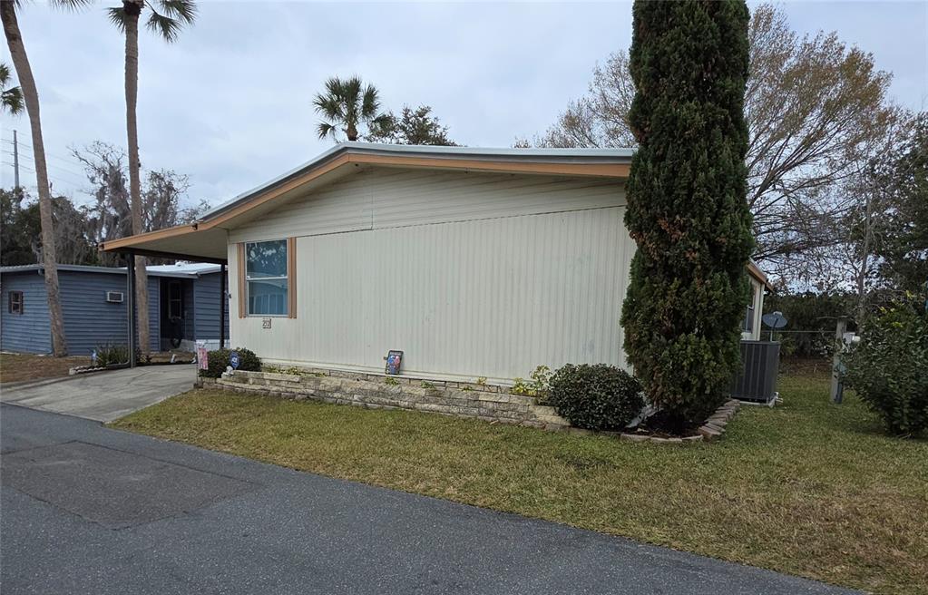 The exterior of a light-colored mobile home features a stone retaining wall and landscaping — 252 PINEWOOD DRIVE, EUSTIS, FL