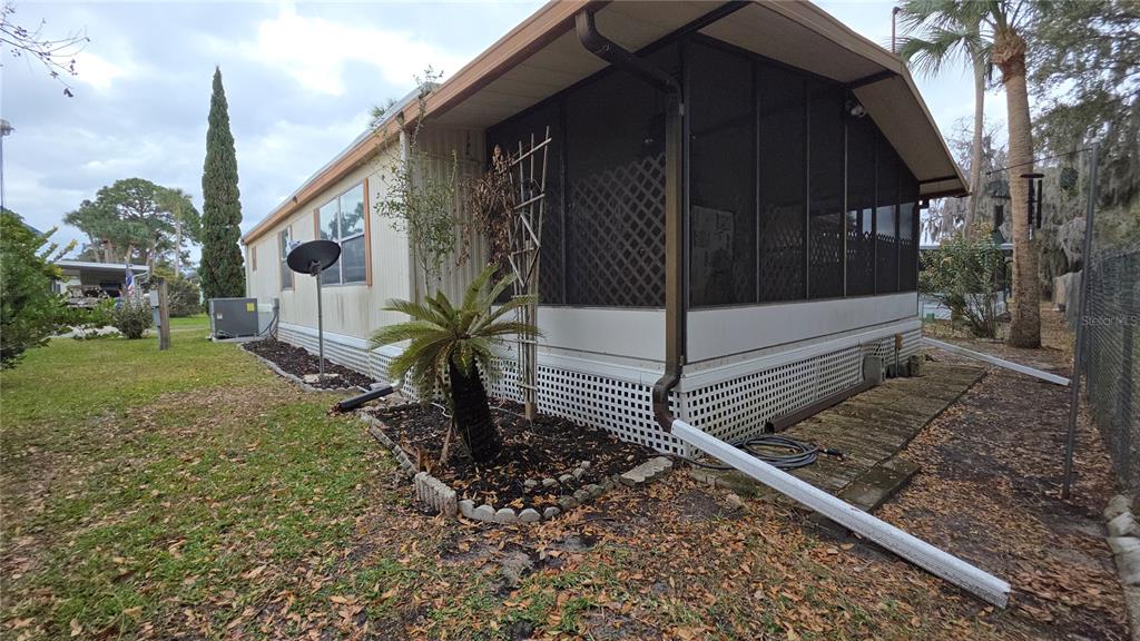 The exterior of a mobile home features a screened-in porch and a white lattice skirting — 252 PINEWOOD DRIVE, EUSTIS, FL