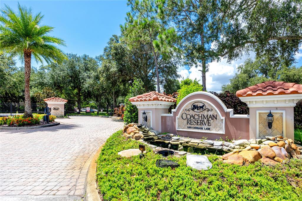 The entrance to a residential community features a stone sign, landscaping, and a paved driveway — 894 LANTERN WAY, CLEARWATER, FL