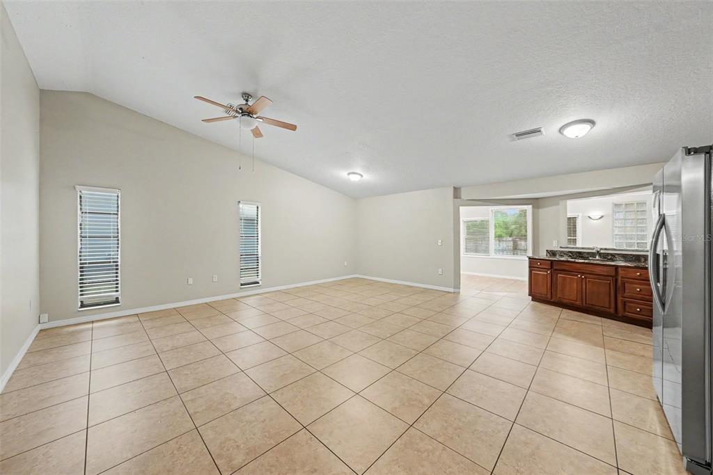 An open-concept kitchen and living area features tile flooring, wood cabinets, and stainless steel appliances — 7623 BRAMBLEWOOD DRIVE, PORT RICHEY, FL