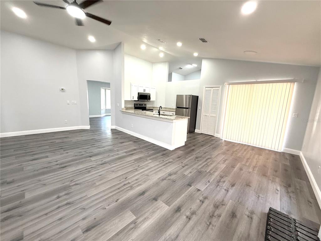 An open-concept living room features gray wood-look flooring, a fireplace, and a kitchen island — 2419 LIELA LEE COURT, OCOEE, FL