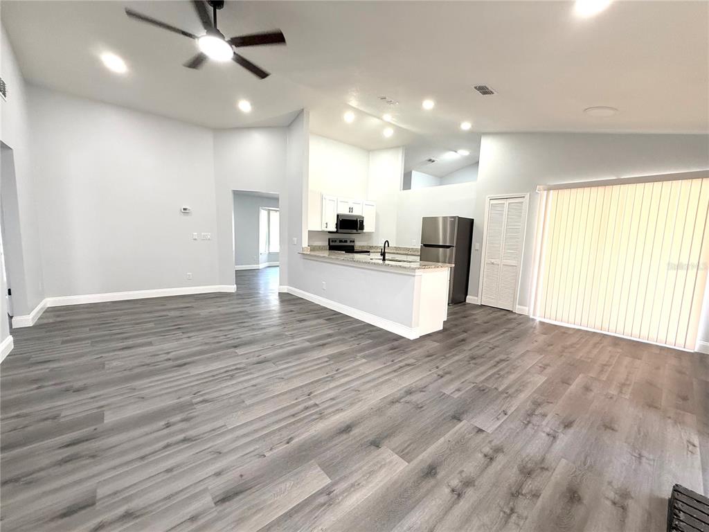An open-concept living area features gray wood-look flooring, a kitchen with white cabinets, and sliding glass doors — 2419 LIELA LEE COURT, OCOEE, FL