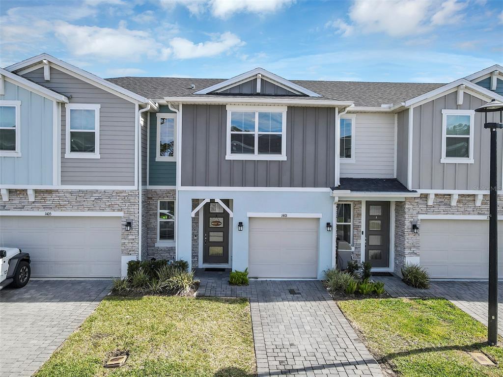 A two-story townhouse with a light blue stucco lower level, gray siding, and a paved driveway — 1401 CAPTIVA COVE UNIT 23, SANFORD, FL