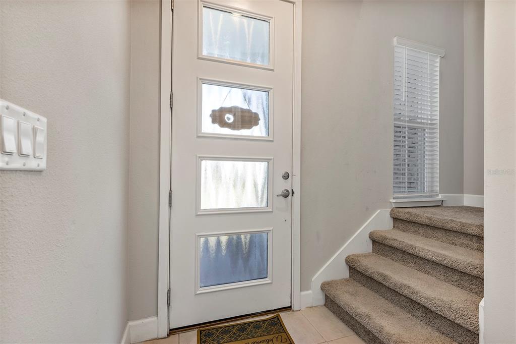 An entryway features a white front door with glass panels, carpeted stairs, and tile flooring — 1401 CAPTIVA COVE UNIT 23, SANFORD, FL