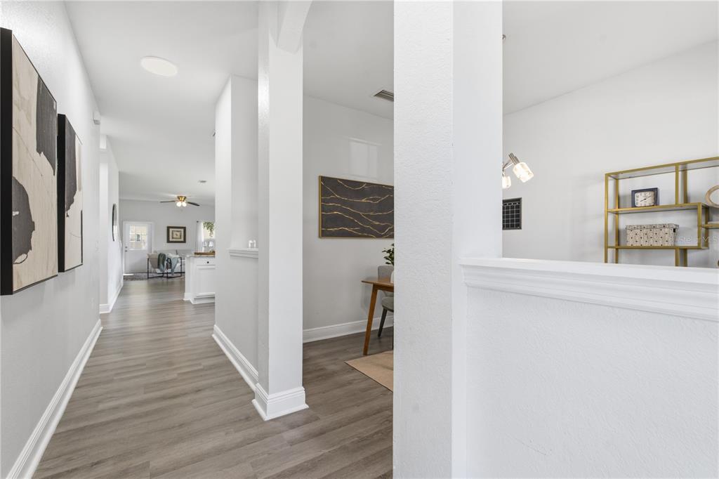 A hallway with wood-look flooring leads to an open living area with white walls — 9530 NATHANIEL LANE, LAND O LAKES, FL