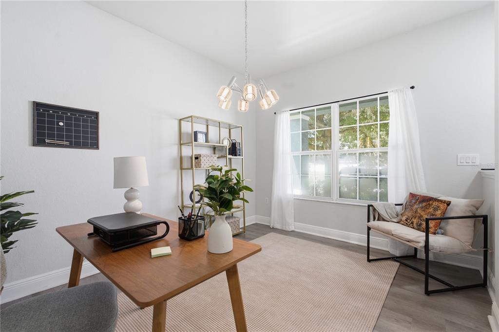 A home office features a wooden desk, a gold bookshelf, a window, and a chair — 9530 NATHANIEL LANE, LAND O LAKES, FL
