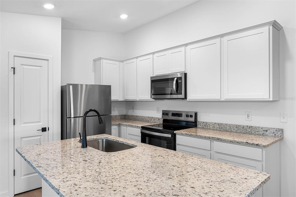 A kitchen features white cabinets, granite countertops, stainless steel appliances, and a central island — 5215 CAP ROAD, BROOKSVILLE, FL