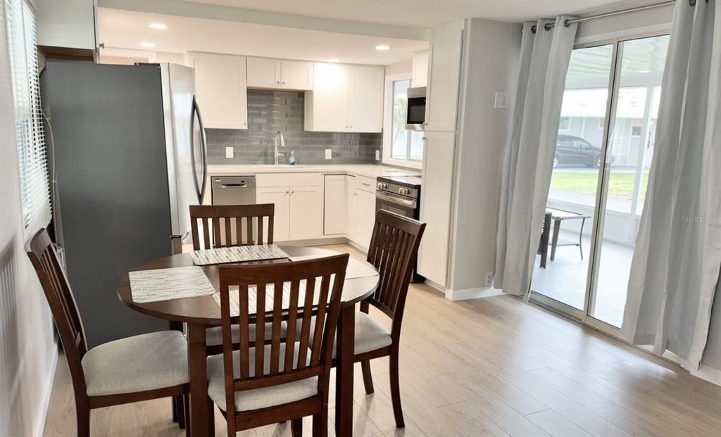 A kitchen features white cabinets, stainless steel appliances, a gray subway tile backsplash, and countertops — 7173 MOUNT BRISTOL BOULEVARD NE UNIT 458, ST PETERSBURG, FL