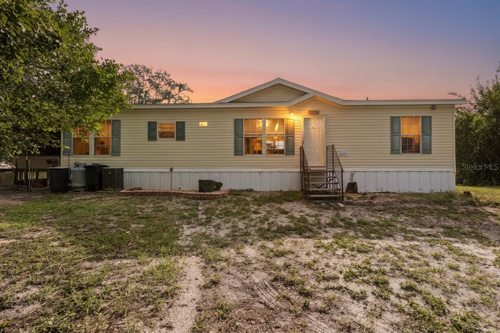 A single-story manufactured home with yellow siding and a front entrance with metal stairs — 6590 CR 631, BUSHNELL, FL