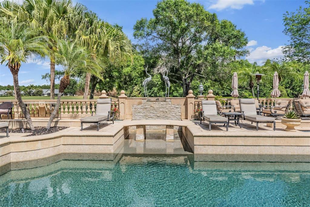 A gated entrance with a stone-accented guardhouse and palm trees under a blue sky — 18707 PEPPER PIKE, LUTZ, FL