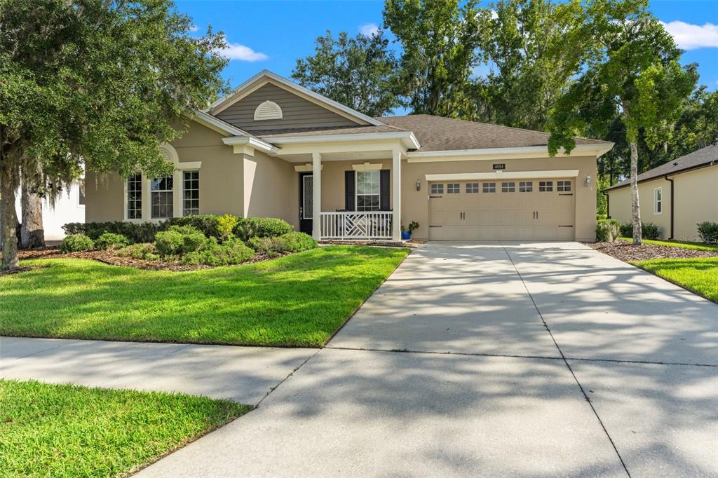 A single-story house with a beige exterior, a two-car garage, and a front porch — 4684 SOUTHERN VALLEY LOOP, BROOKSVILLE, FL