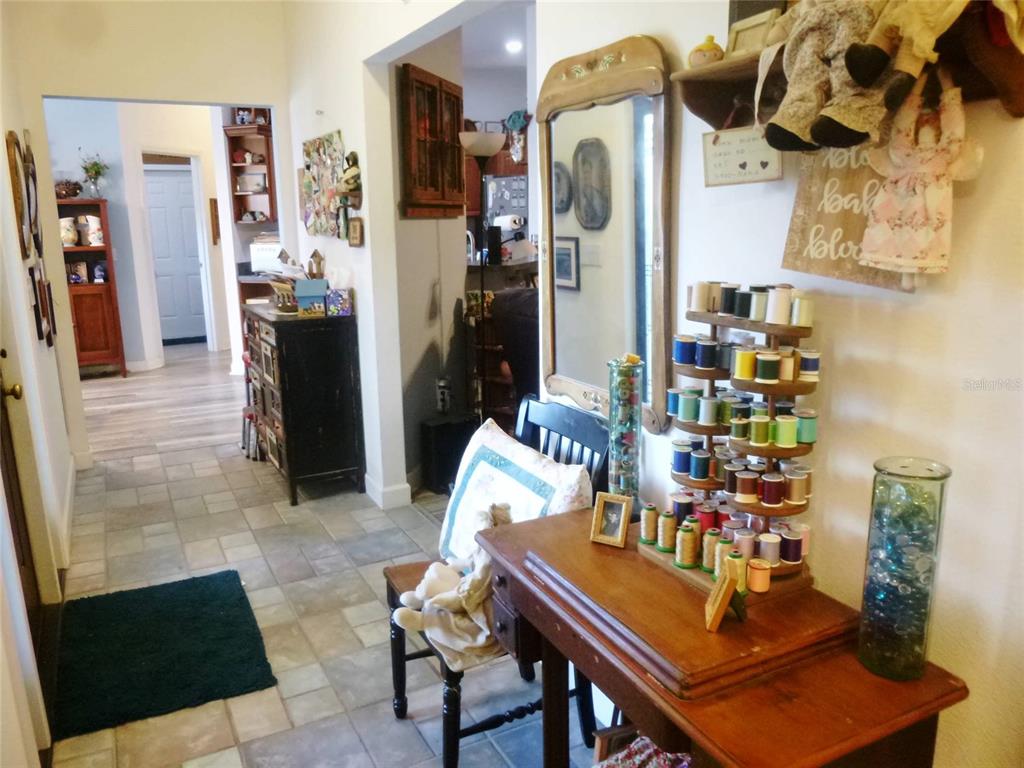 A sewing area with a thread rack and wooden table sits in a tiled hallway — 121 DEER ROAD, FROSTPROOF, FL
