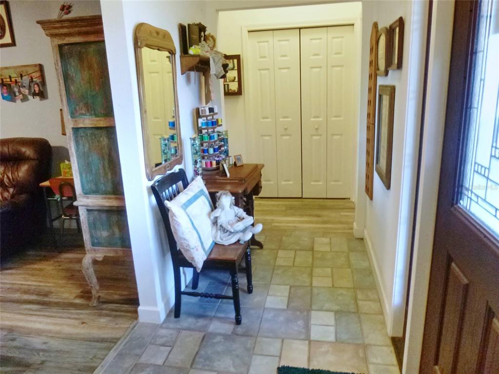 An entryway features tile flooring, a wooden chair with a doll, and a hallway closet — 121 DEER ROAD, FROSTPROOF, FL