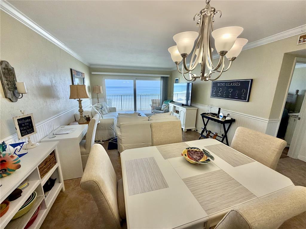 A dining area and living room overlook the ocean through large sliding glass doors — 4801 SAXON DR. UNIT A 202, NEW SMYRNA BEACH, FL