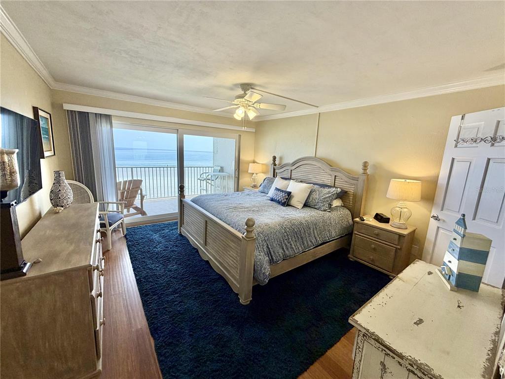 A bedroom features a king bed, dark blue rug, and a balcony overlooking the ocean — 4801 SAXON DR. UNIT A 202, NEW SMYRNA BEACH, FL