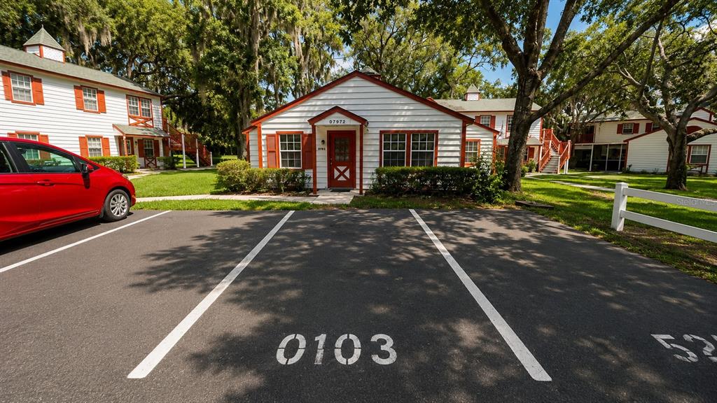 A white building with red trim and a red door sits behind a parking lot — 7972 MIDWAY DRIVE TERRACE UNIT O103, OCALA, FL