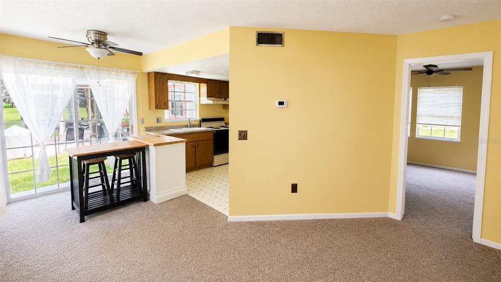 A yellow-walled living area opens to a kitchen with wood cabinets and a sliding door — 7972 MIDWAY DRIVE TERRACE UNIT O103, OCALA, FL