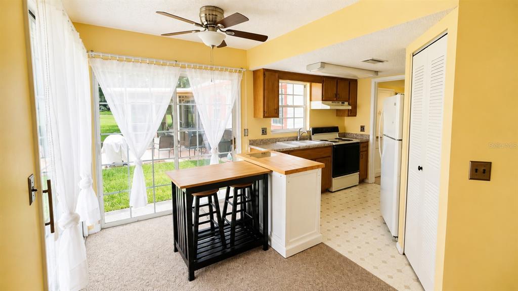 A kitchen with wooden cabinets, a white island, and a sliding glass door to a patio — 7972 MIDWAY DRIVE TERRACE UNIT O103, OCALA, FL