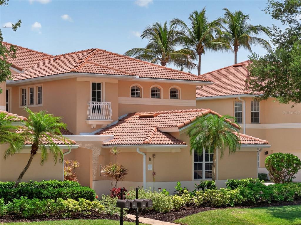 A multi-story stucco building with a terracotta tile roof and palm trees in the foreground — 3336 SUNSET KEY CIRCLE UNIT D, PUNTA GORDA, FL