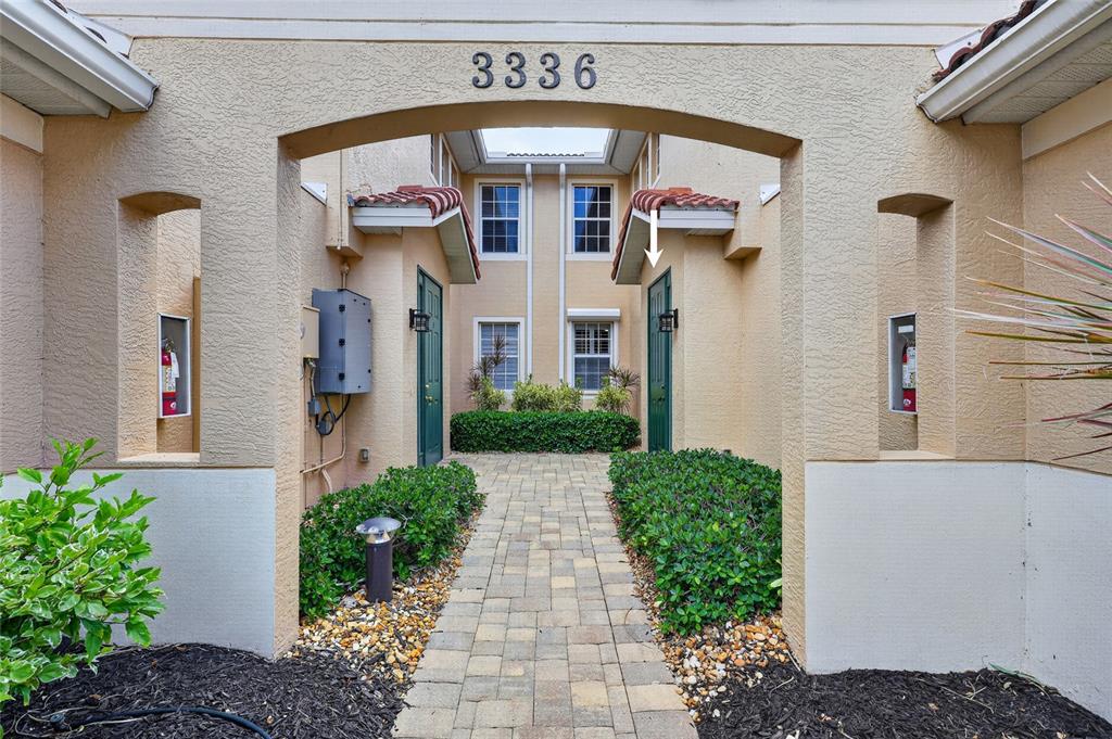 An exterior view of a building entrance with a stone walkway and two green doors — 3336 SUNSET KEY CIRCLE UNIT D, PUNTA GORDA, FL