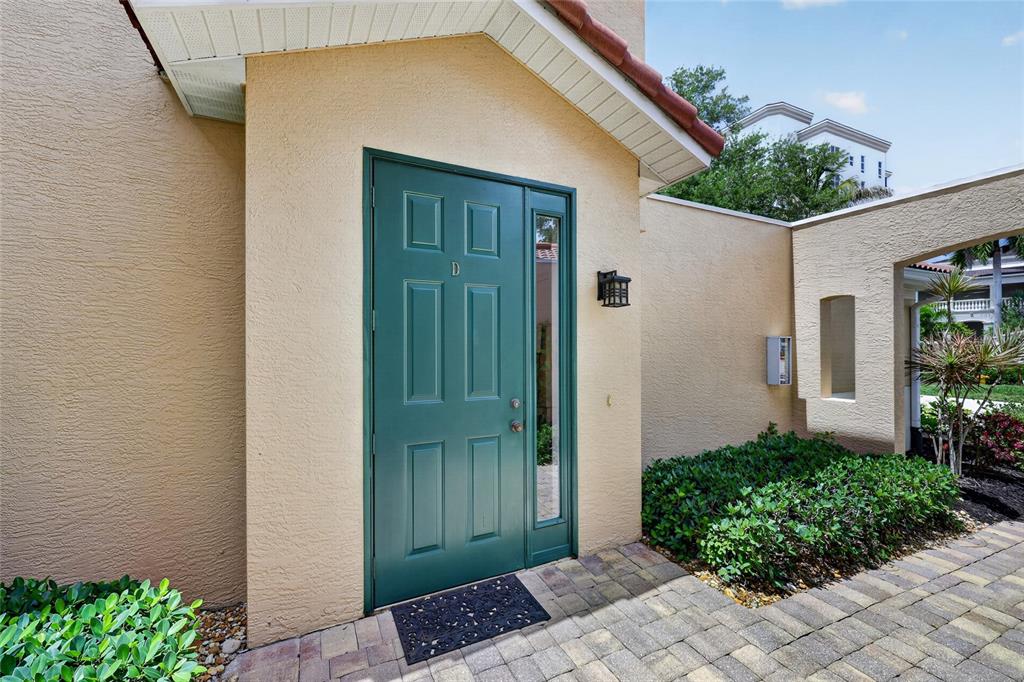 A green front door with a sidelight is set in a tan stucco exterior wall — 3336 SUNSET KEY CIRCLE UNIT D, PUNTA GORDA, FL