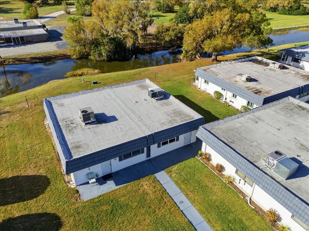 The exterior of a single-story house features a metal roof and a screened-in porch — 205 ANDOVER PLACE N UNIT 119, SUN CITY CENTER, FL