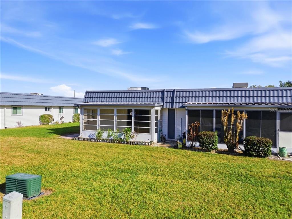 A view of the rear exterior of a single-story home with a screened-in porch — 205 ANDOVER PLACE N UNIT 119, SUN CITY CENTER, FL