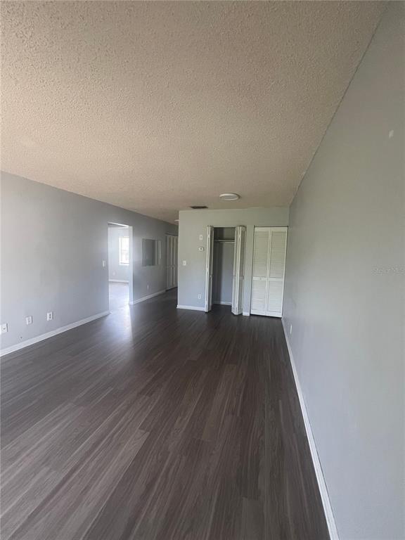 An empty room with gray walls, dark wood-look flooring, and a white bi-fold closet door — 709 OCEANSIDE CIRCLE UNIT 712, RUSKIN, FL